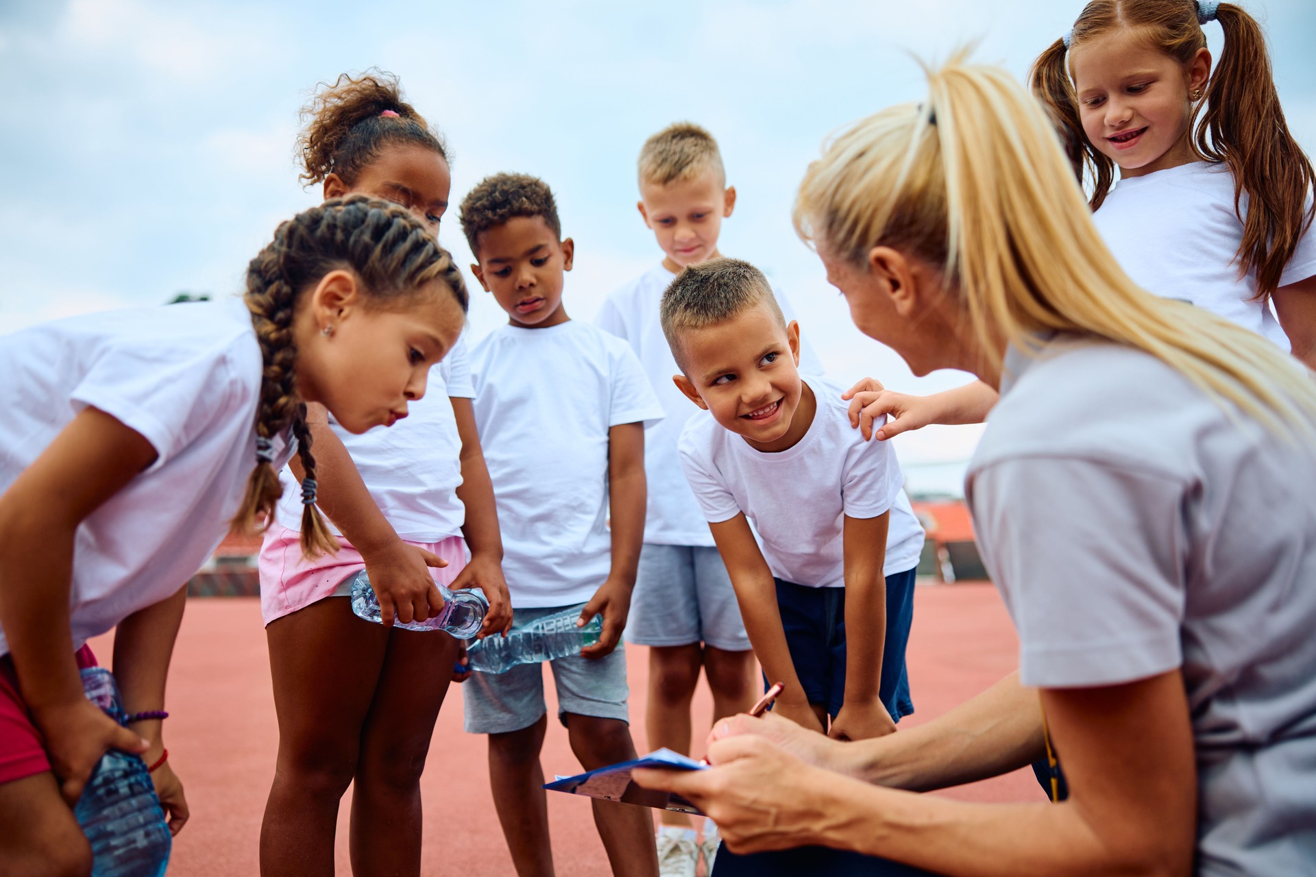 Group of kids and their coach going through exercise plan during sports training.