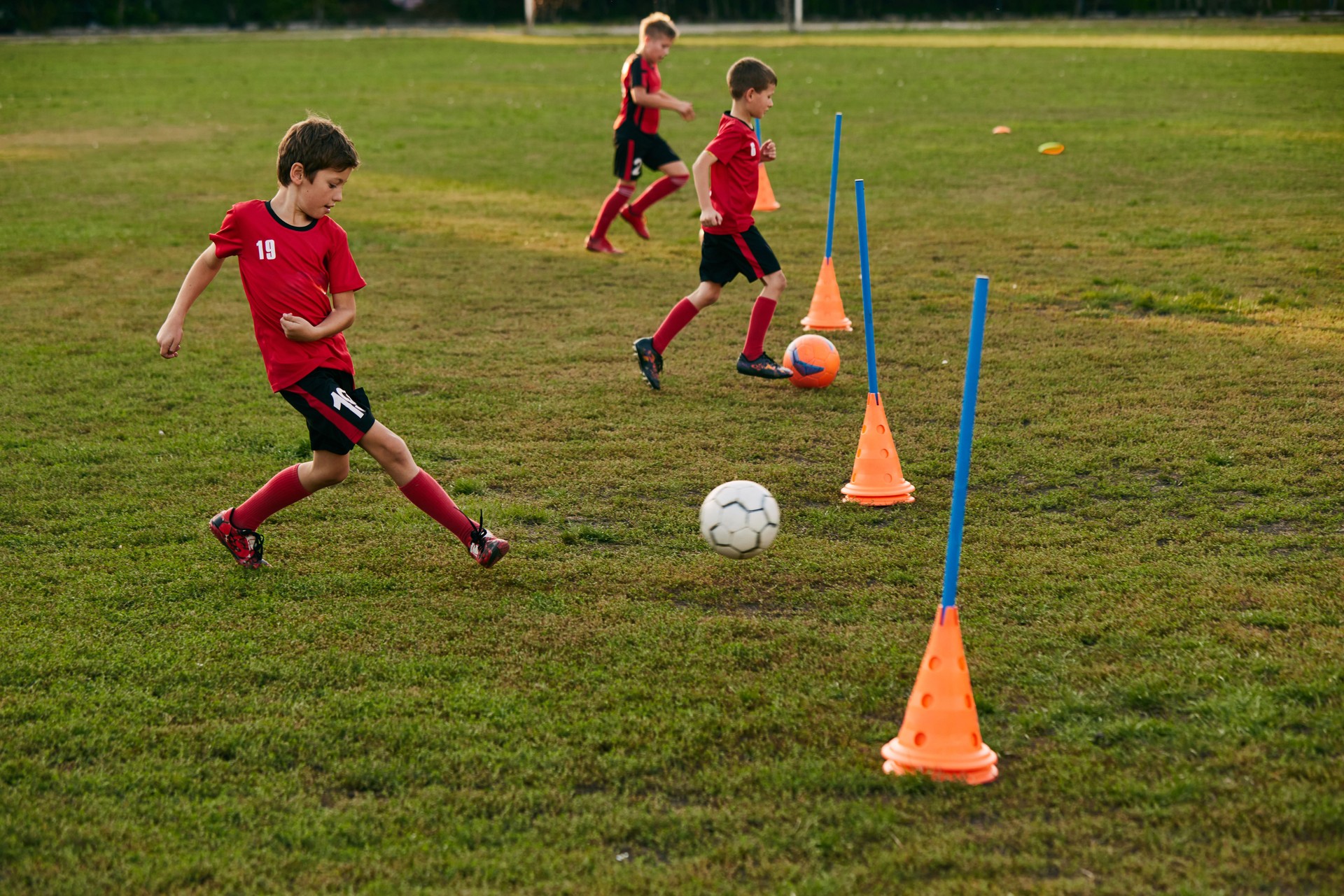 Kid soccer player in sport uniform training dribble ball, prepare to match on football field in motion. Playing football. Children's team games.